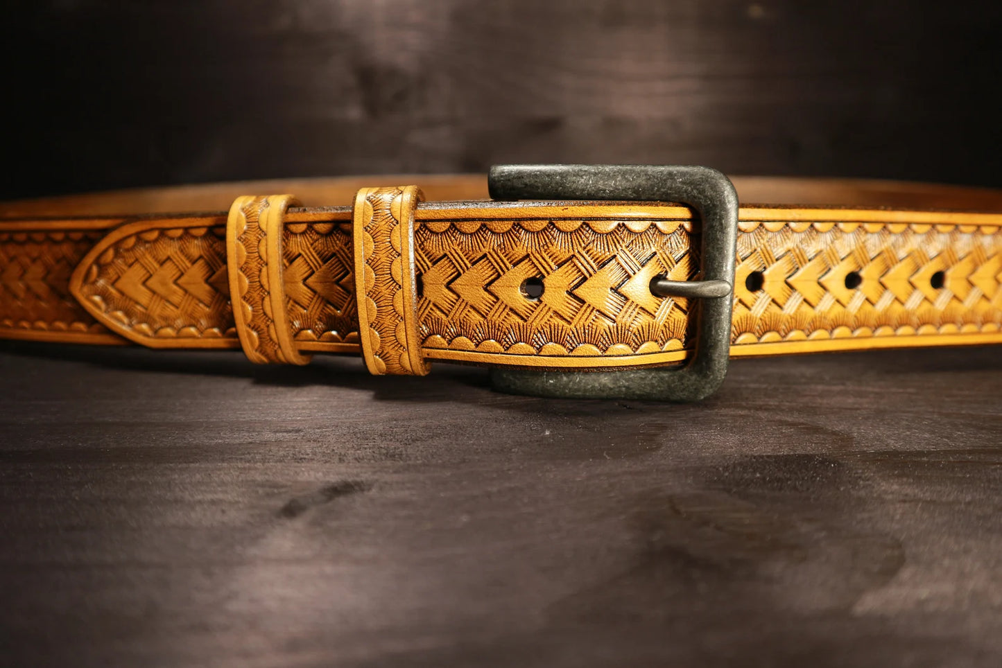 Detail ručního basket ražení na koženém opasku z třísločiněné hovězí kůže s kovovou přezkou.