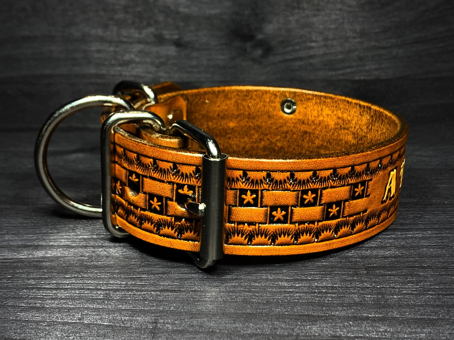 Detail koženého obojku pro psa s masivním kovovým zapínáním, D-kroužkem na vodítko a ručně raženým vzorem